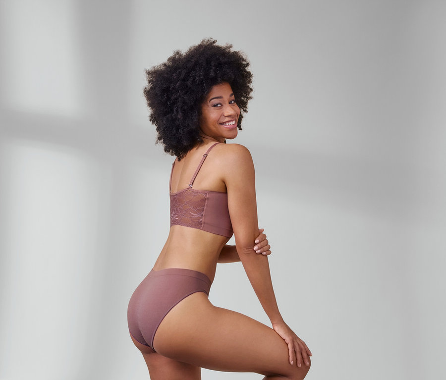 Frau posiert in braunem Seamless-Bustier mit Spitze und 2 Seamless-Slips, braun.