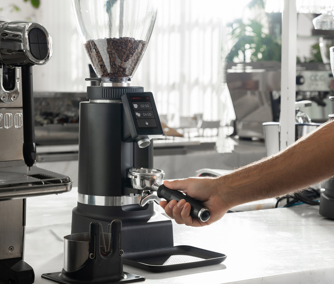 Mann befüllt Siebträger mit einer schwarzen Kaffeemühle.