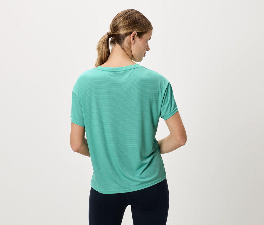 Rückansicht einer Frau mit Pferdeschwanz, die ein türkisfarbenes Sportoberteil und marineblaue Leggings trägt.
