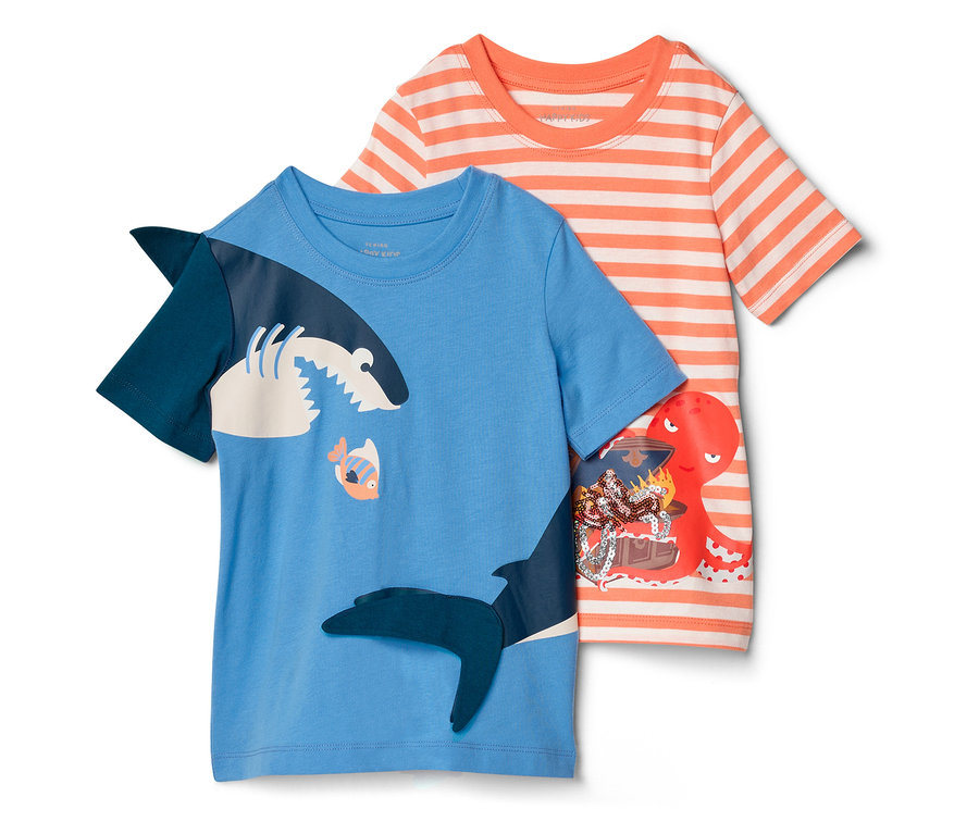 Zwei Kinder-T-Shirts liegen nebeneinander: ein blaues mit Hai-Motiv und ein orange-weiß gestreiftes mit Krake und Schatztruhe.