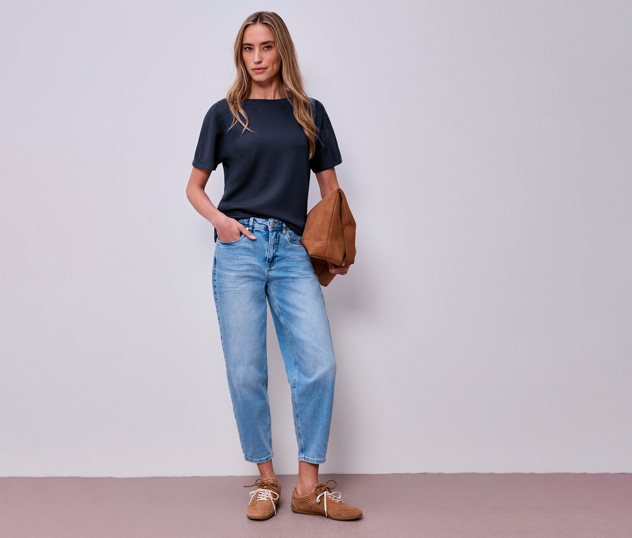 Frau in Jeans und marineblauem Street One Kurzarmshirt mit Tasche in der Hand.