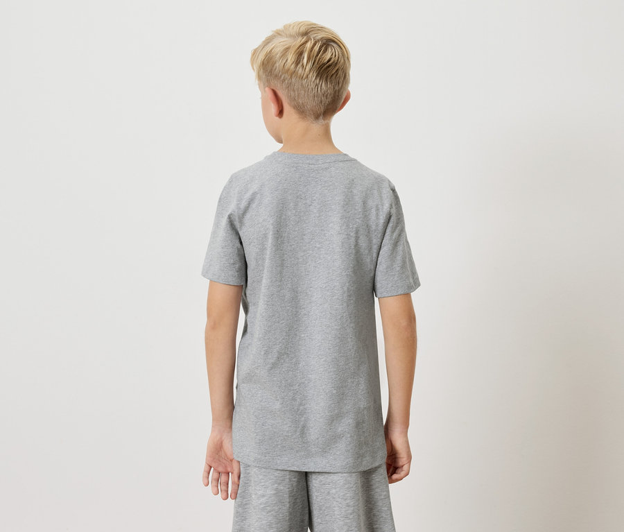 Rückansicht eines Jungen mit blonden Haaren, der ein graues T-Shirt und Shorts vor einem neutralen Hintergrund trägt.