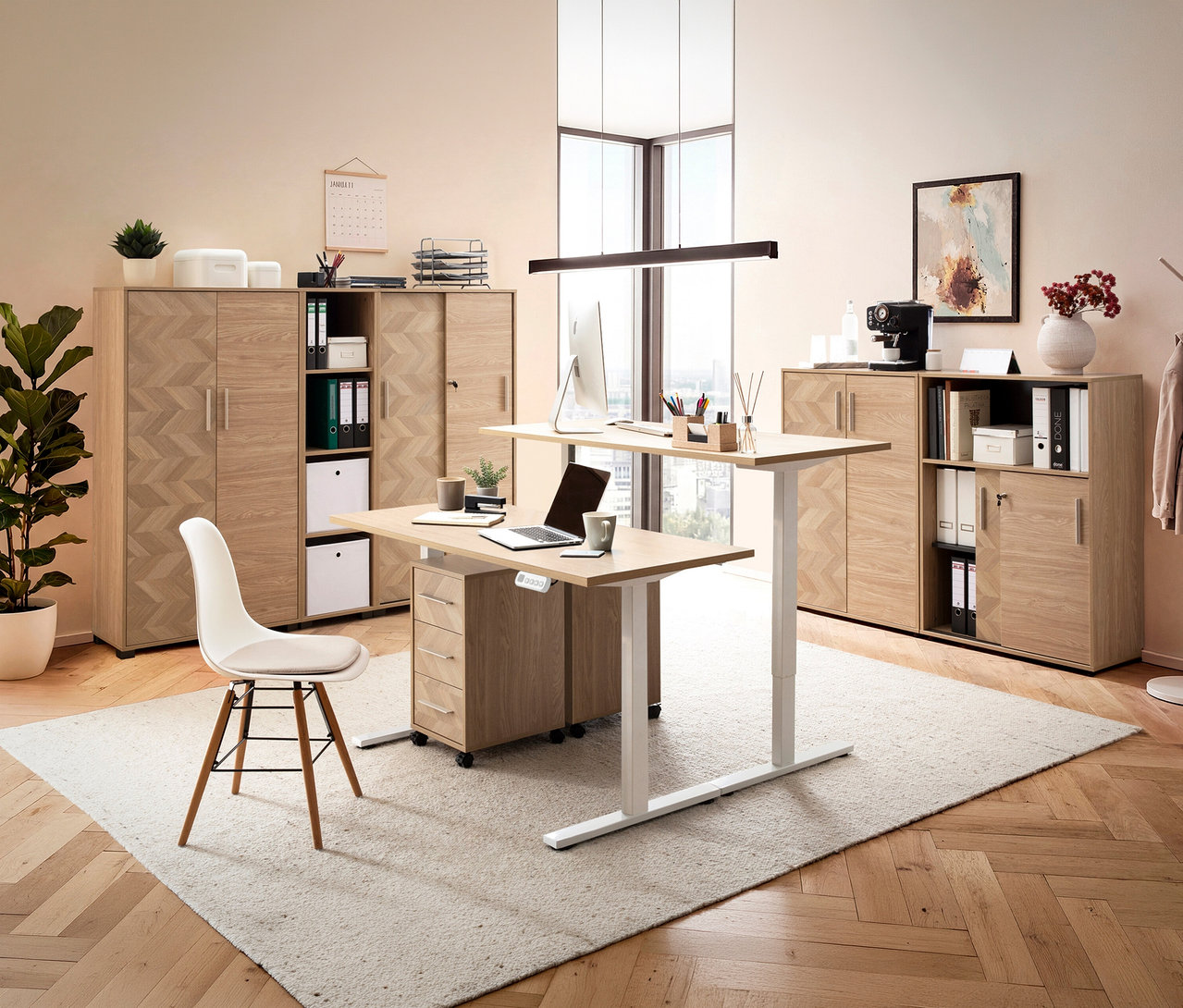 Büro mit höhenverstellbarem Schreibtisch, Bürostuhl, Aktenschrank und Deko in hellem Raum mit Parkettboden und Teppich.