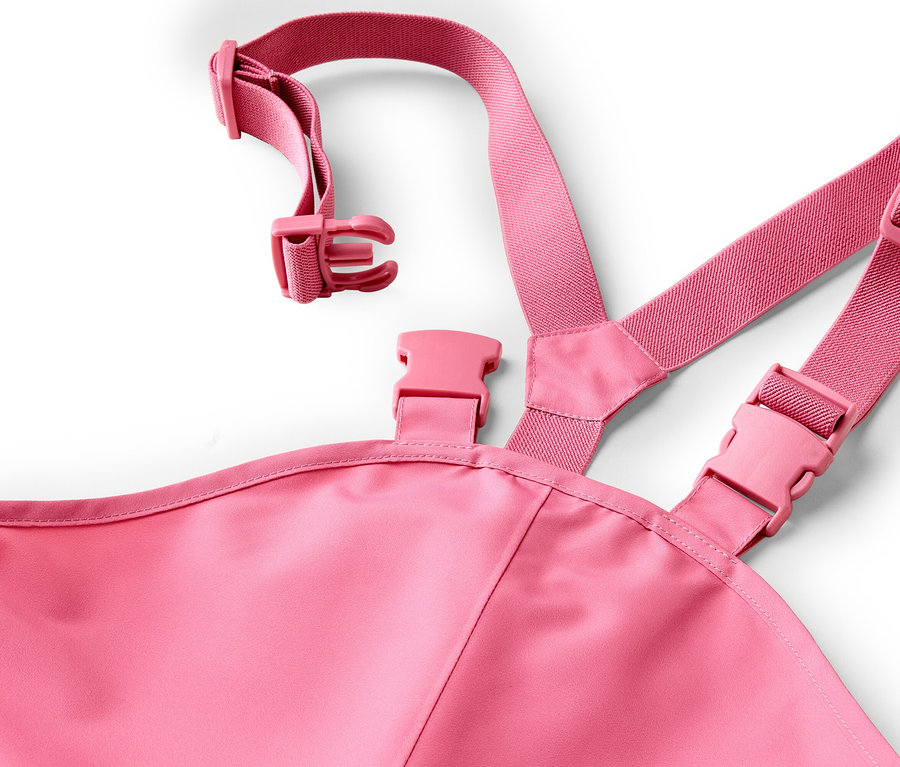 Nahaufnahme einer pinkfarbenen Latzhose mit verstellbaren Trägern und Schnallen auf weißem Hintergrund.