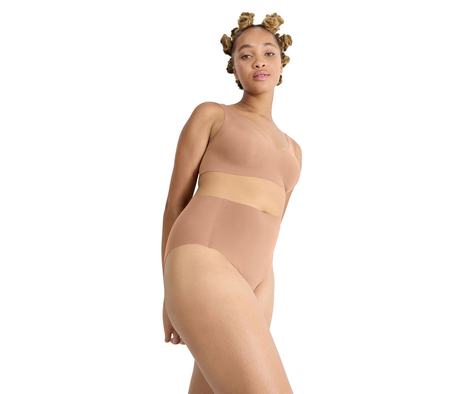 Frau mit dunkler Haut und Bantu-Knoten trägt einen hellbraunen BH und passende sloggi ZERO Feel 2.0 High Waist Höschen in Nostalgic Brown.