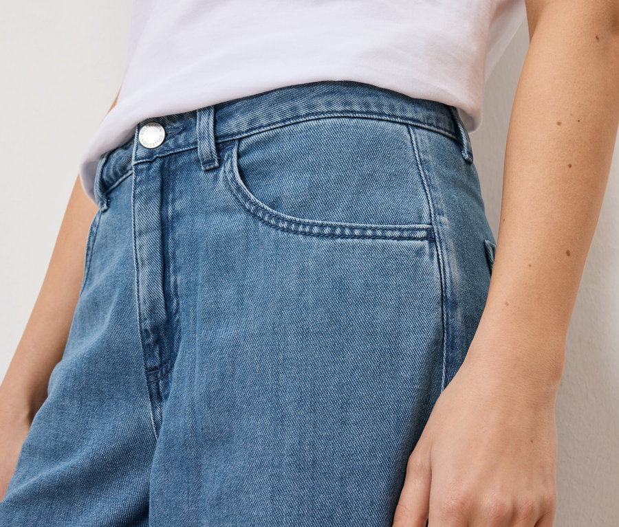 Nahaufnahme einer Frau in hellblauen Jeans und einem weißen T-Shirt.