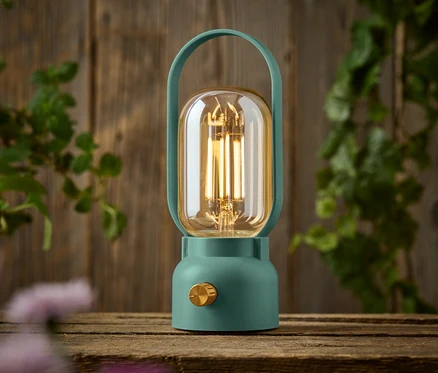Eine grüne Lampe mit einem goldenen Knopf steht auf einem Holztisch.