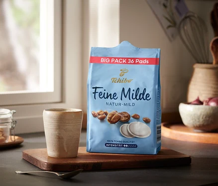 Eine Packung Feine Milde Pads - 36 Pads steht neben einer Tasse auf einem Holztablett.