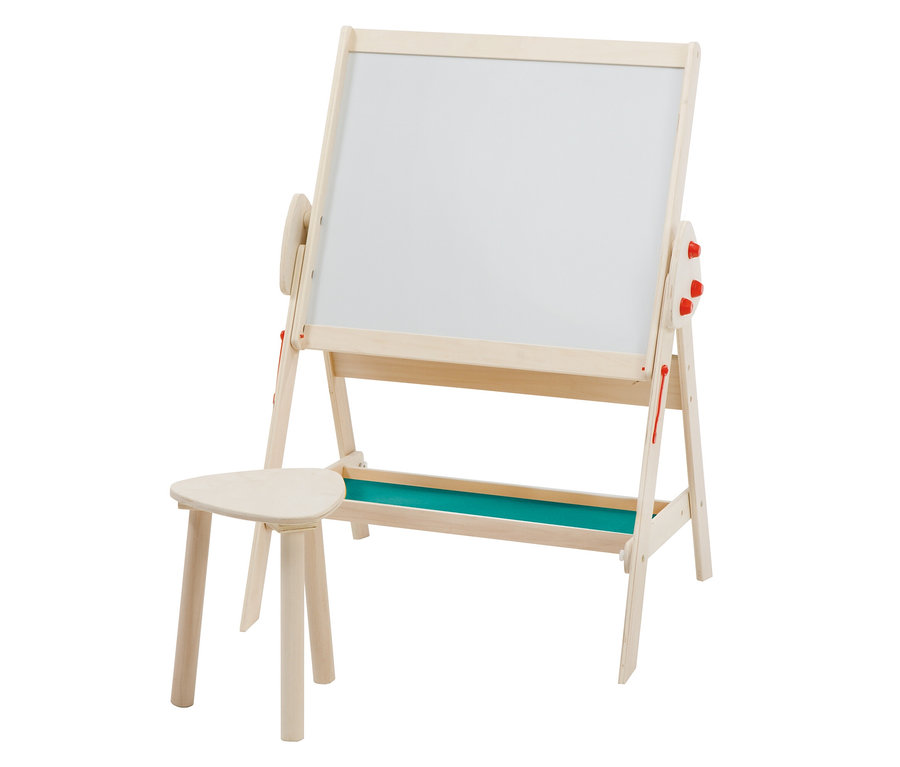 Eine helle Kinder-Staffelei aus Holz mit einer weißen Tafel, einer grünen Ablage unten und roten Verstellknöpfen an den Seiten. Daneben steht ein kleiner, heller dreibeiniger Holzschemel.