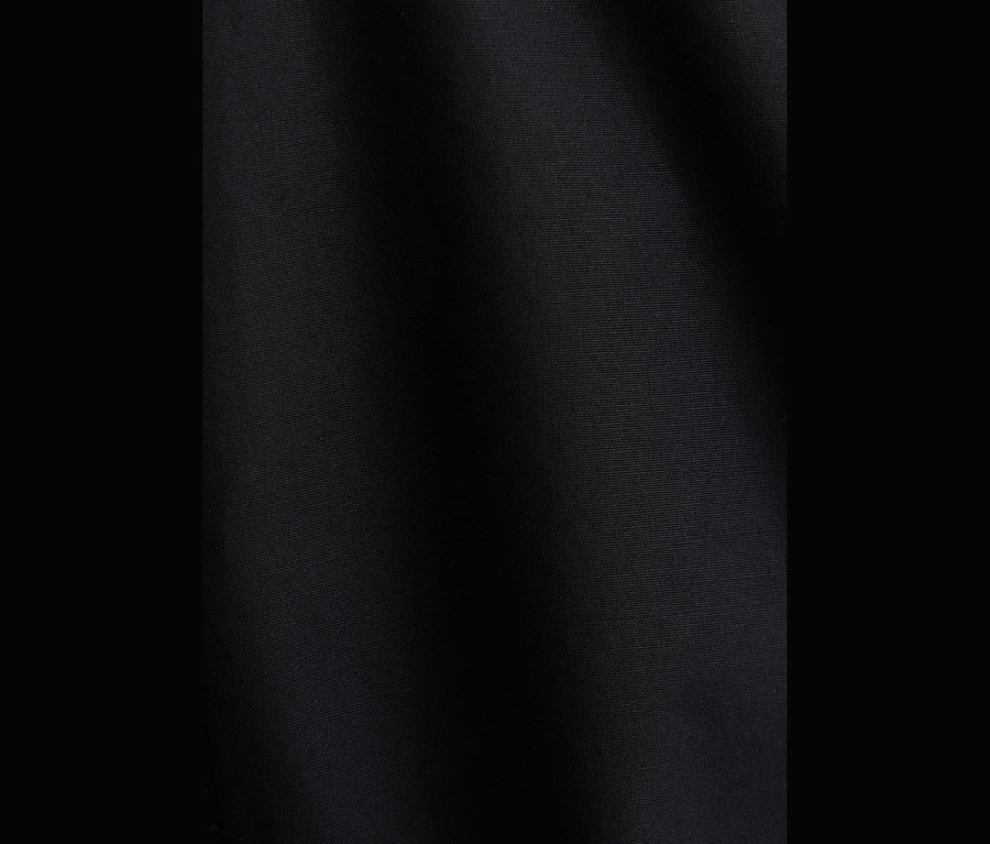 Nahaufnahme von schwarzem Popeline-Stoff, wahrscheinlich einer Popeline-Bluse, mit sichtbarer Textur und leichten Falten.
