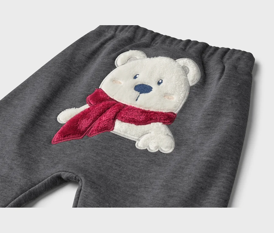Dunkelgraue Jogginghose mit einer flauschigen, weißen Eisbären-Applikation, der einen roten Schal trägt.