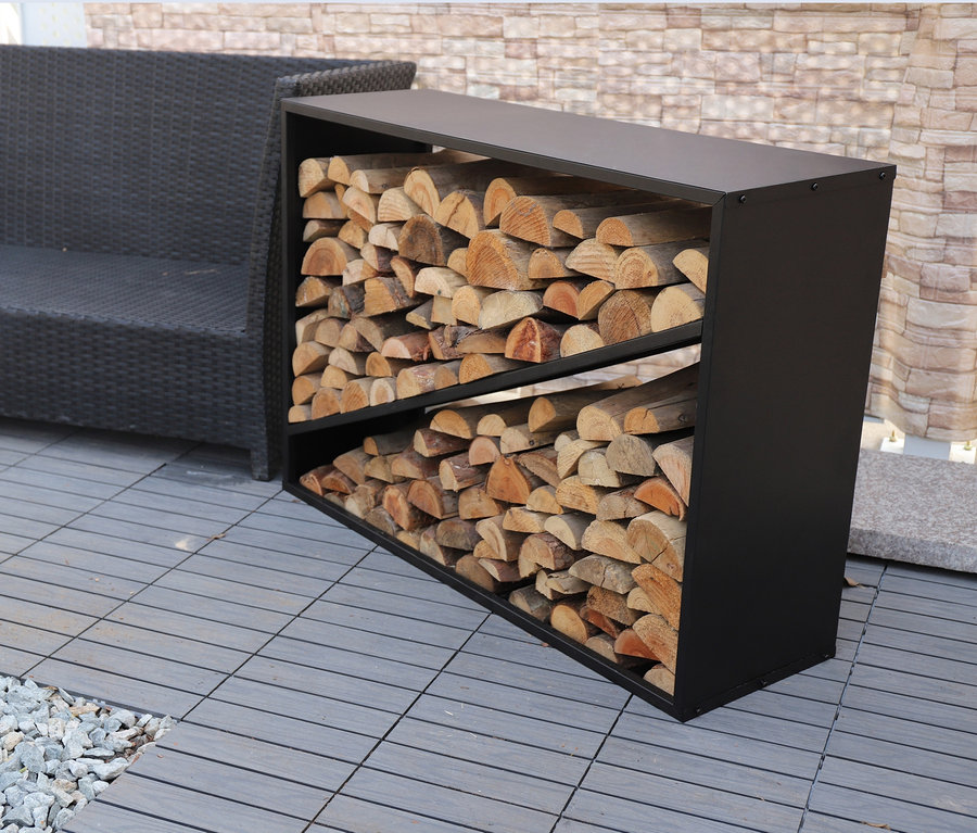 Ein ca. 114 cm großes Kaminholzregal gefüllt mit Holzscheiten steht draußen neben einem grauen Sofa.
