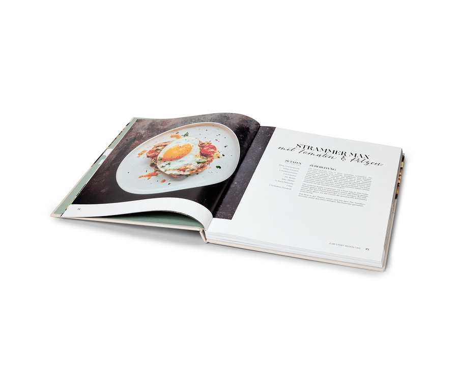 Aufgeschlagenes Kochbuch, auf einer Seite ein Foto von einem Gericht, auf der anderen Seite ein Rezept.