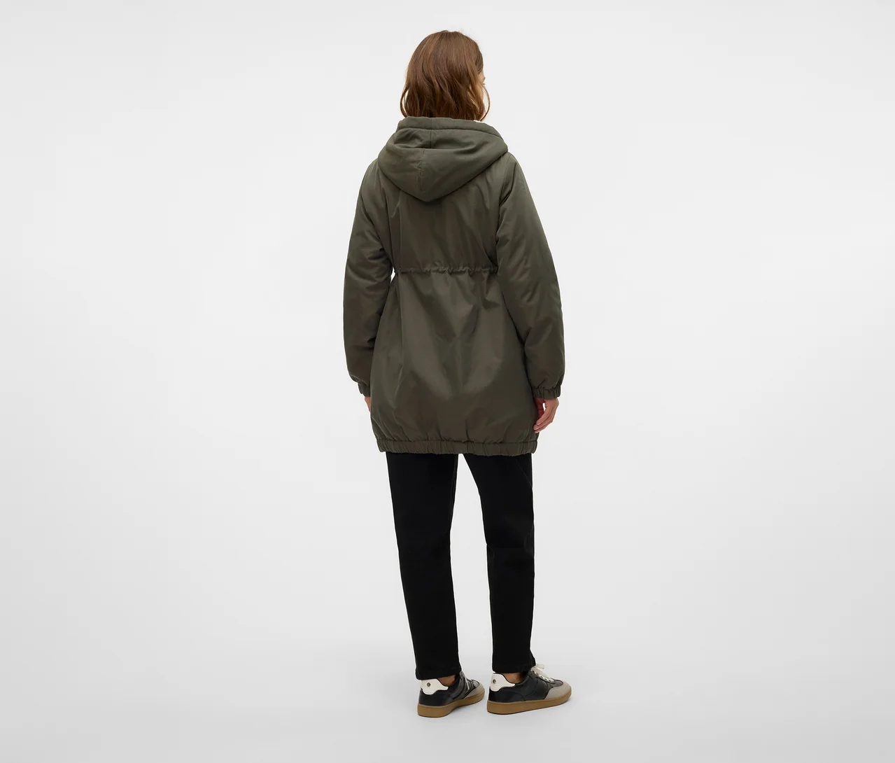 Person von hinten, trägt eine dunkelgrüne Kapuzenjacke mit Kordelzug in der Taille, schwarze Hose und dunkle Sneaker.