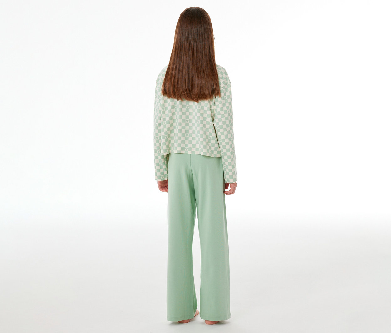 Kind von hinten in einem SCHIESSER Kinder-Interlock-Pyjama. Das langärmelige Oberteil ist hellgrün-weiß kariert, die Hose ist einfarbig hellgrün.