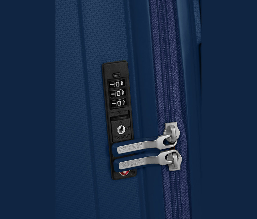 Nahaufnahme eines navyblauen American Tourister #Rejoy Spinner# Koffers mit einem Zahlenschloss und zwei Reißverschlussziehern.