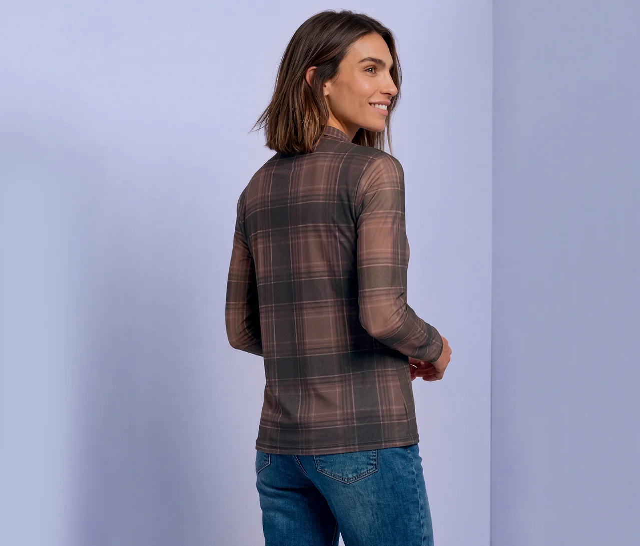 Frau mit kurzen braunen Haaren, die ein braunes kariertes Street One Mesh-Shirt und Jeans trägt und über die Schulter blickt.
