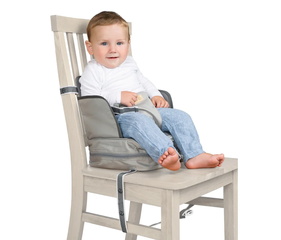 Ein Junge sitzt in einem grauen roba Boostersitz »Little Star«, der an einem Holzstuhl befestigt ist.