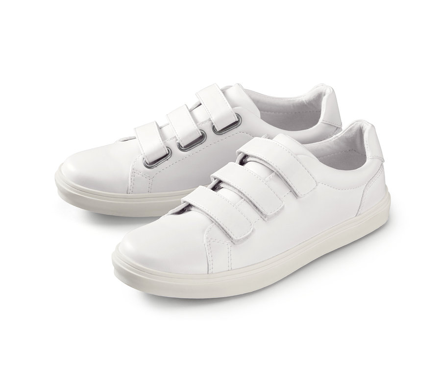 Zwei weiße Sneaker mit Klettverschluss liegen nebeneinander.