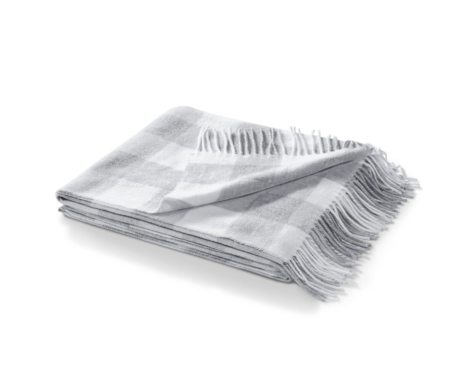 Eine gefaltete, grau karierte Wohndecke mit Fransen.
