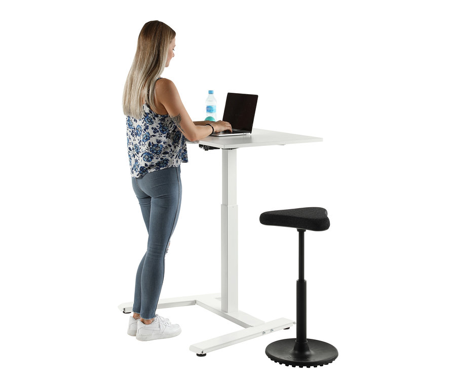 Frau steht an weissem Topstar E-Tisch »Single« und benutzt Laptop. Neben dem Tisch steht ein schwarzer Stuhl.