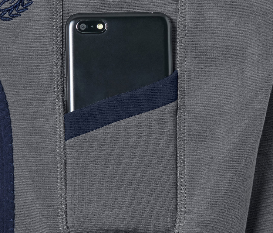 Ein Smartphone steckt in der Tasche einer Vollbesatzreithose.