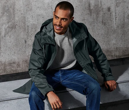 Mann sitzt in Outdoor-Jacke auf Bank.