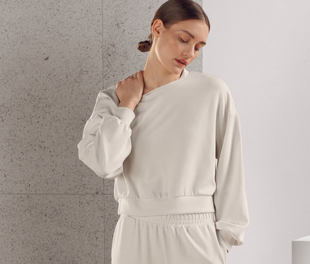 Frau posiert in extraweichem beigen Trainingsanzug, bestehend aus Pullover und Hose.