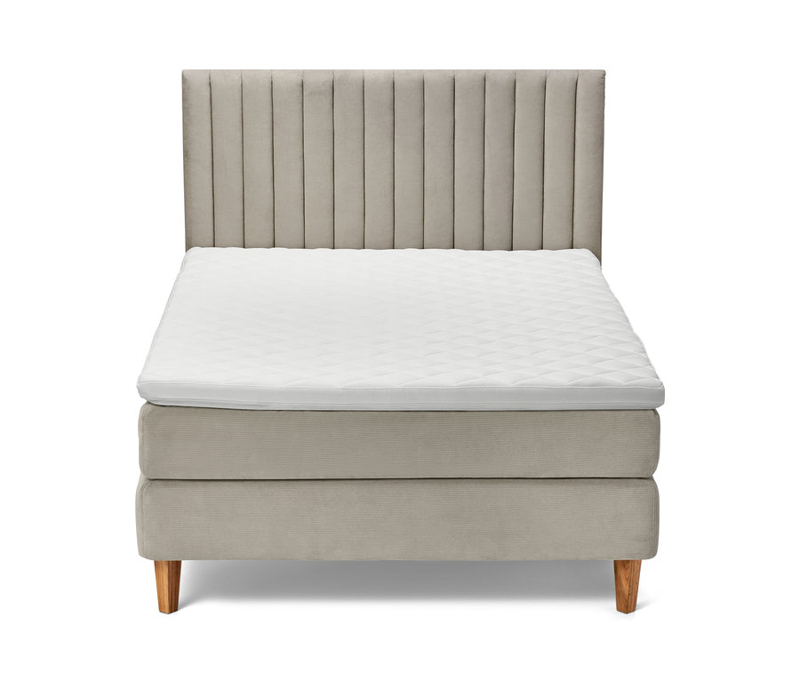 Beiges Boxspringbett mit Kopfteil und weißer Matratze.