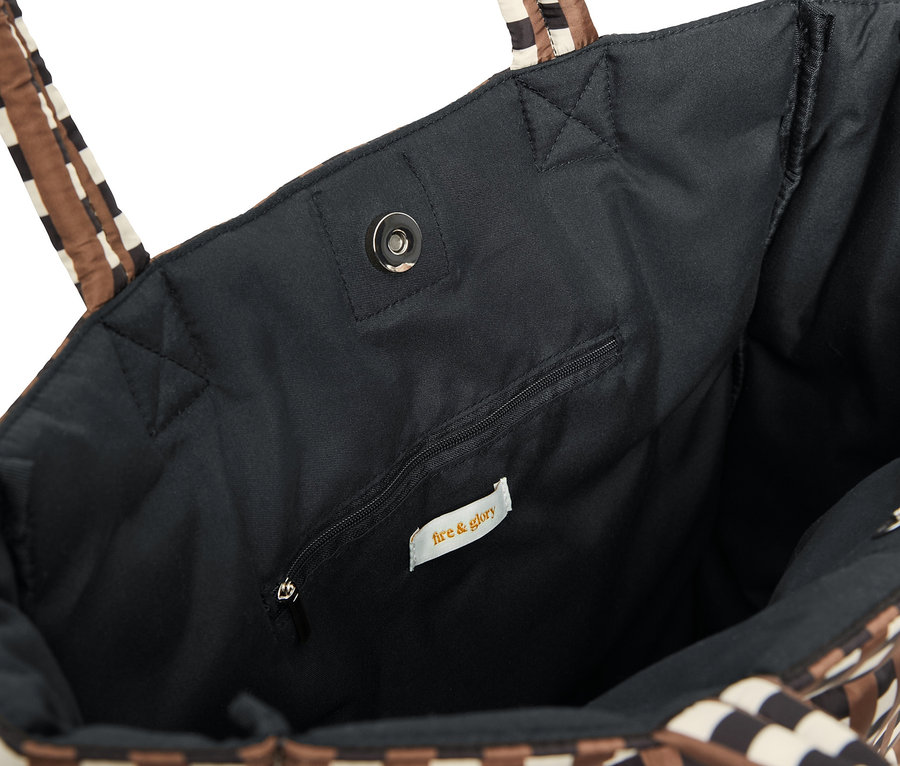 Detailaufnahme einer gesteppten Tasche mit schwarzem Innenfutter und gestreiften Henkeln.