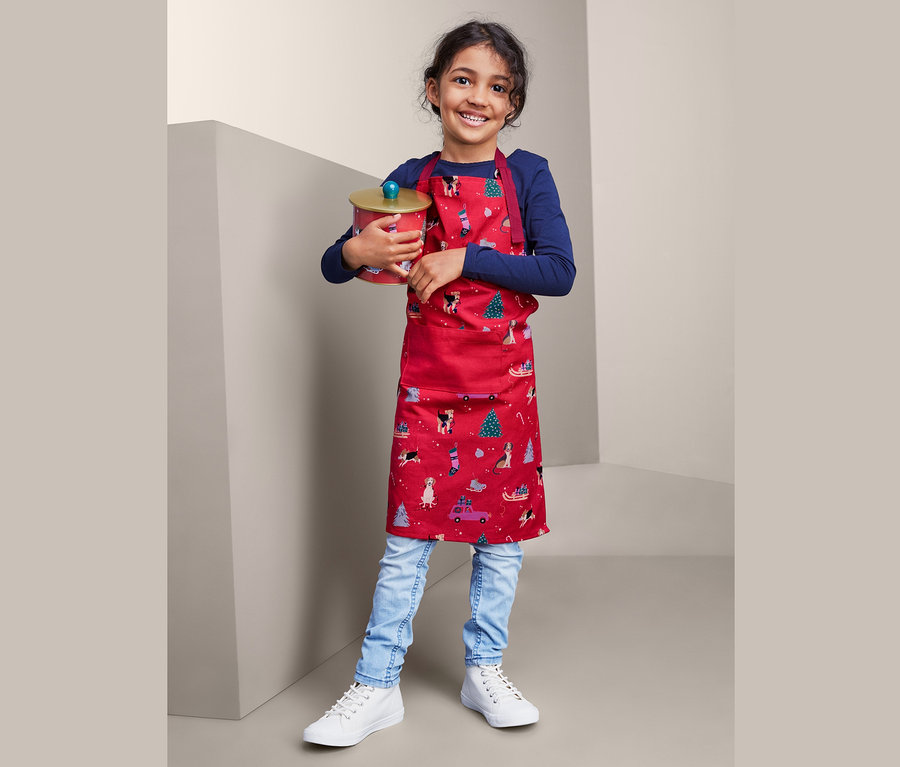 Mädchen in Küchenschürze hält Dose.