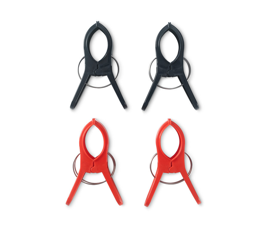 Vier Handtuchclips: zwei schwarze und zwei rote.