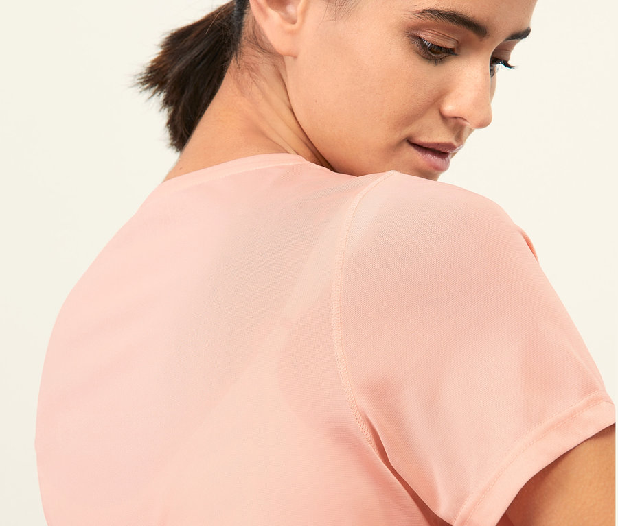 Detailaufnahme einer jungen Frau mit dunklen Haaren in einem rosafarbenen Sportshirt.