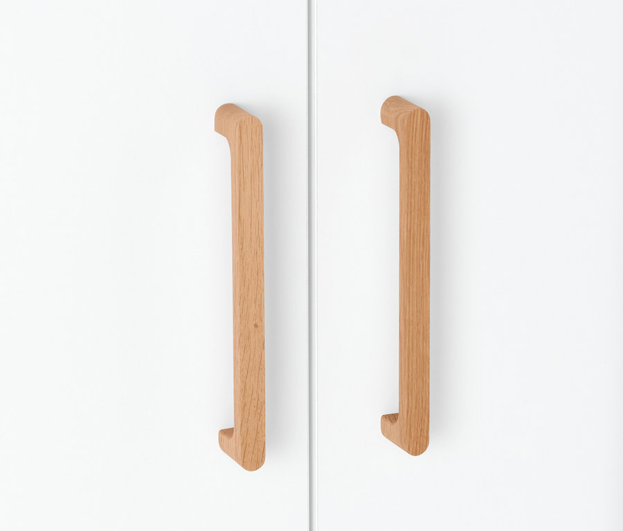 Detail einer weißen Schranktür mit Holzgriffen.