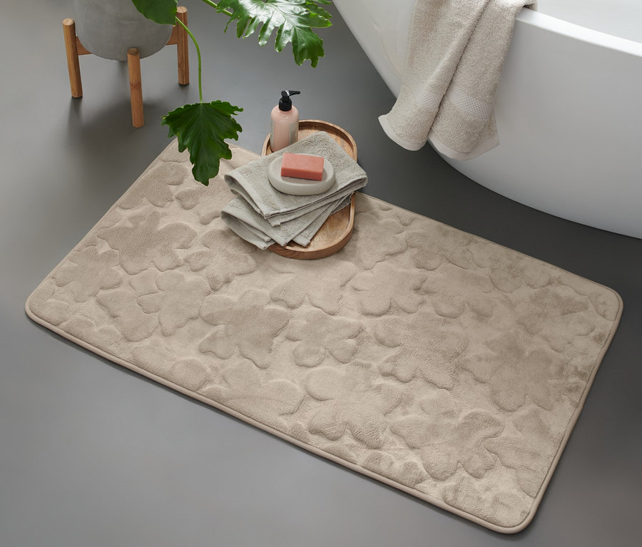 Eine beige Komfort-Badematte, ca. 60 x 100 cm, liegt auf dem Boden neben einer Badewanne.