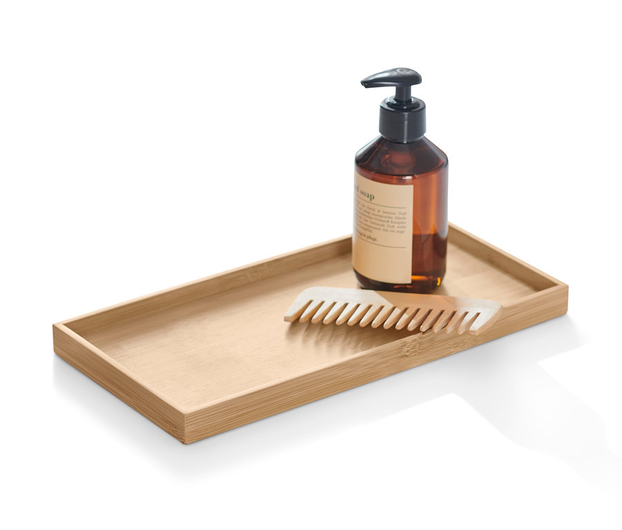 Braune Flasche mit Pumpspender und Kamm liegen auf einem dekorativen Tablett.