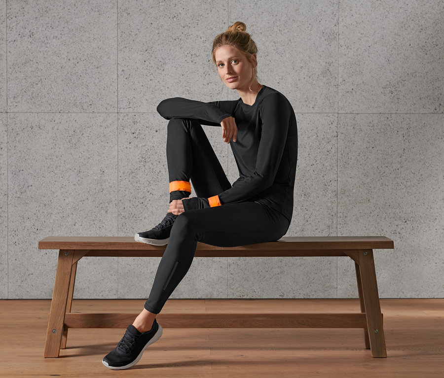 Frau sitzt auf Bank, trägt 2 LED-Schnappbänder mit USB am Handgelenk.