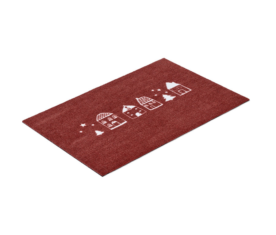 Eine rote Textil-Fußmatte mit weißen Häusern und Weihnachtsbäumen.