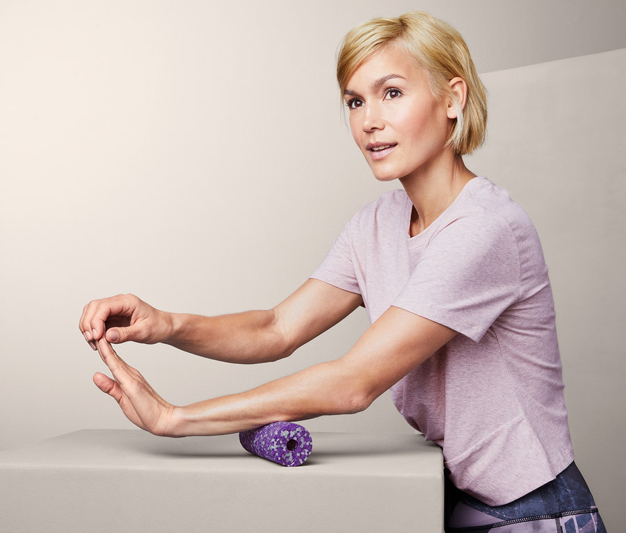 Blonde Frau verwendet Mini-Faszienrolle auf ihrem Arm.