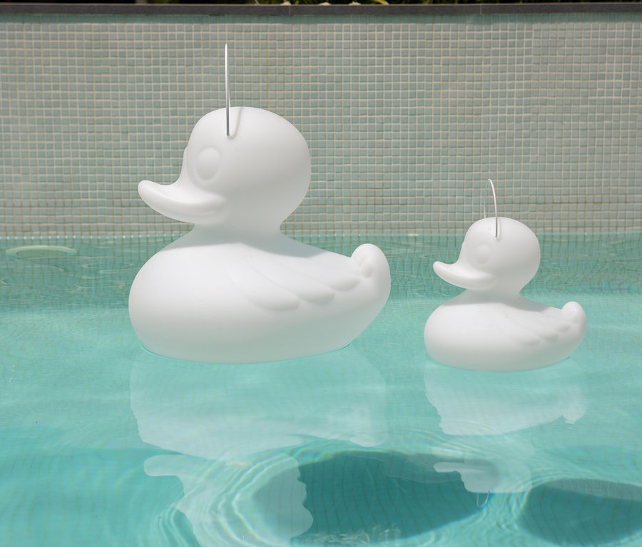 Zwei weiße Goodnight Light LED-Leuchten »Ente« (S und XL) schwimmen im Wasser.