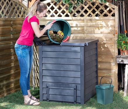 Frau mit Pferdeschwanz leert Inhalt aus Eimer in Garantia Thermo-Wood Komposter im Garten.