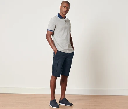 Mann steht mit Händen in den Taschen der navy Cargo-Shorts.