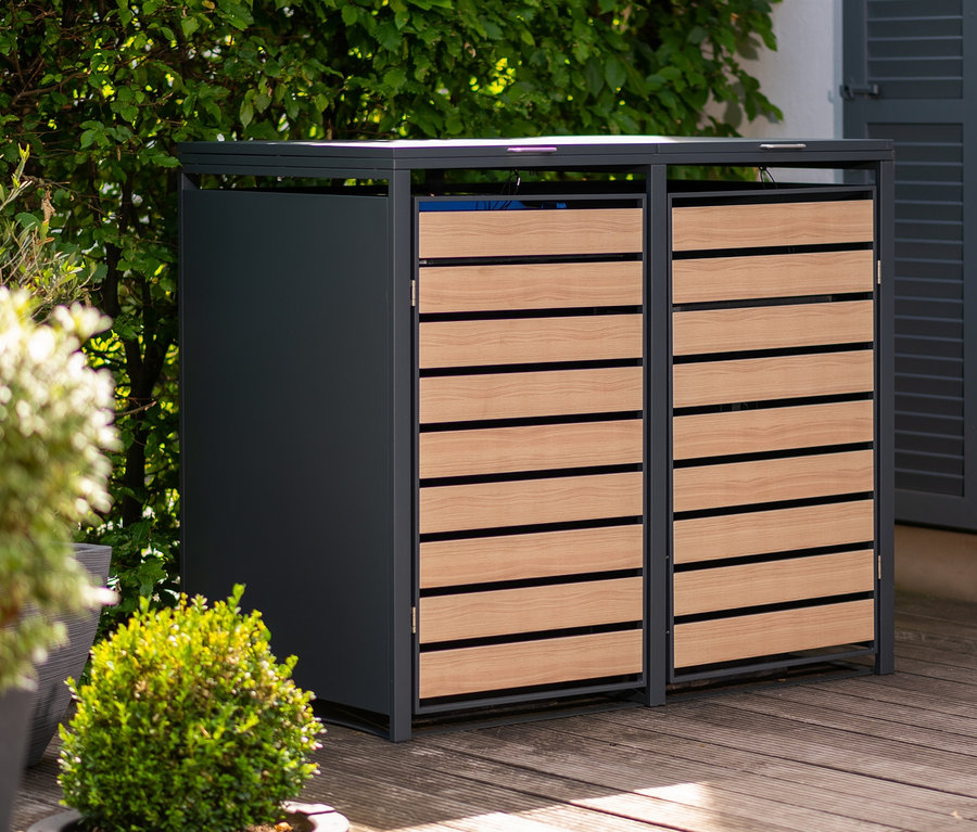 Eine Mülltonnenbox, 2er aus Metall und Holz steht auf einer Holzterrasse.