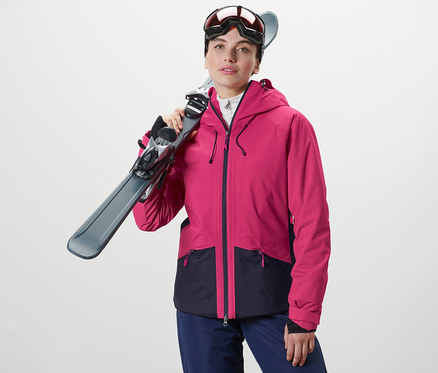 Frau hält Ski über der Schulter. Sie trägt eine Skijacke.