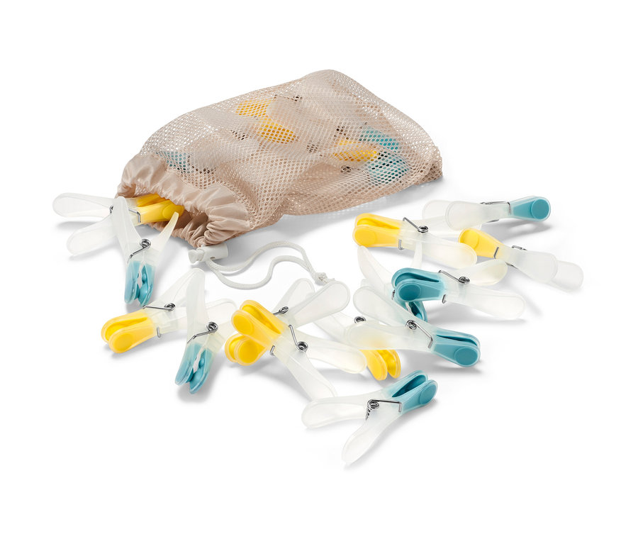 20 Wäscheklammern liegen neben einem beigen Netzbeutel.