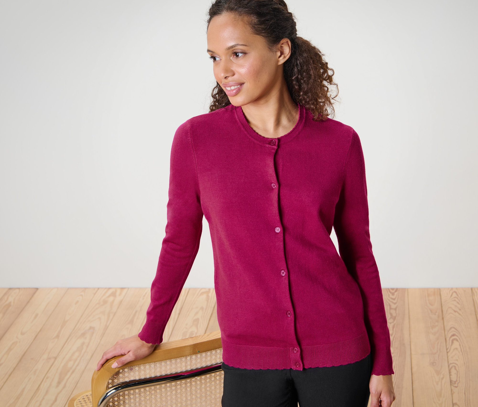 Frau mit gewelltem Haar posiert in Feinstrick-Cardigan mit Wellenkante.