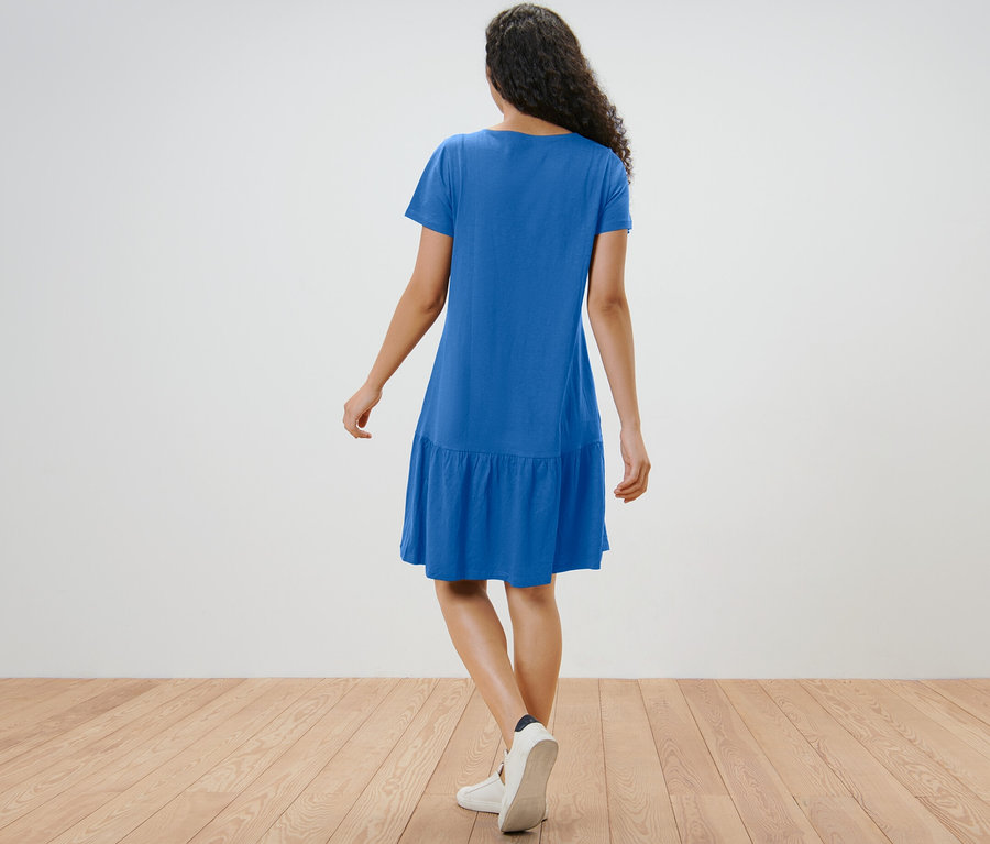 Frau von hinten in kobaltblauem Jerseykleid mit Volant.