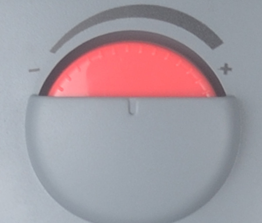 Nahaufnahme eines Drehreglers mit roter Anzeige und Skala von Minus nach Plus. Zu sehen ist ein Ölheizgerät »99405«.