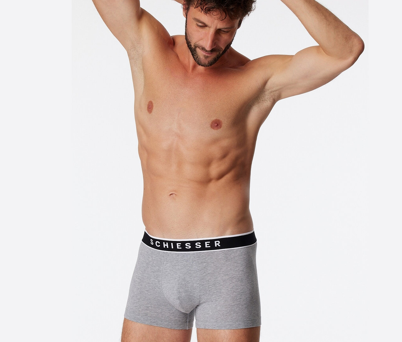 Mann mit Händen hinter dem Kopf trägt 3 SCHIESSER Shorts mit Bio-Baumwolle, grau meliert.