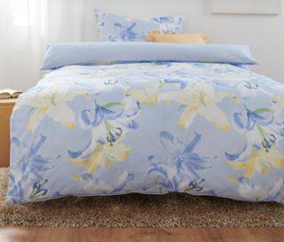 Blaues Bett mit Blumenmuster und Premium-Baumwoll-Bettwäsche.